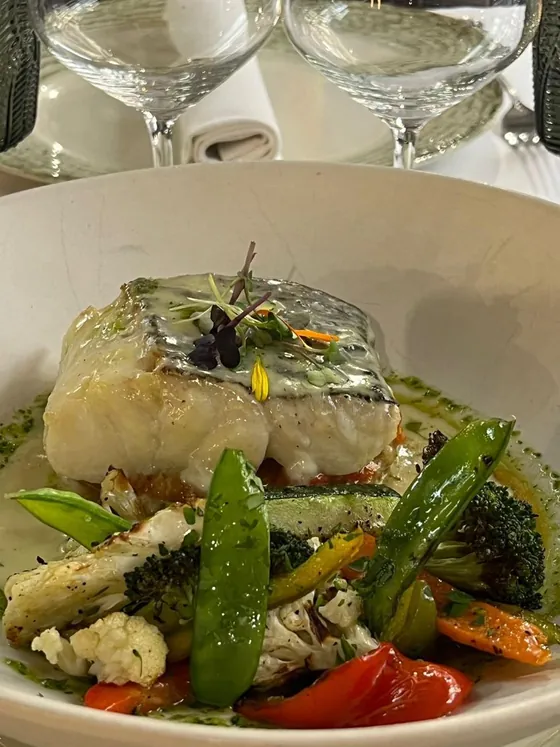 Un lomo de pescado blanco sobre verduras, en un plato hondo